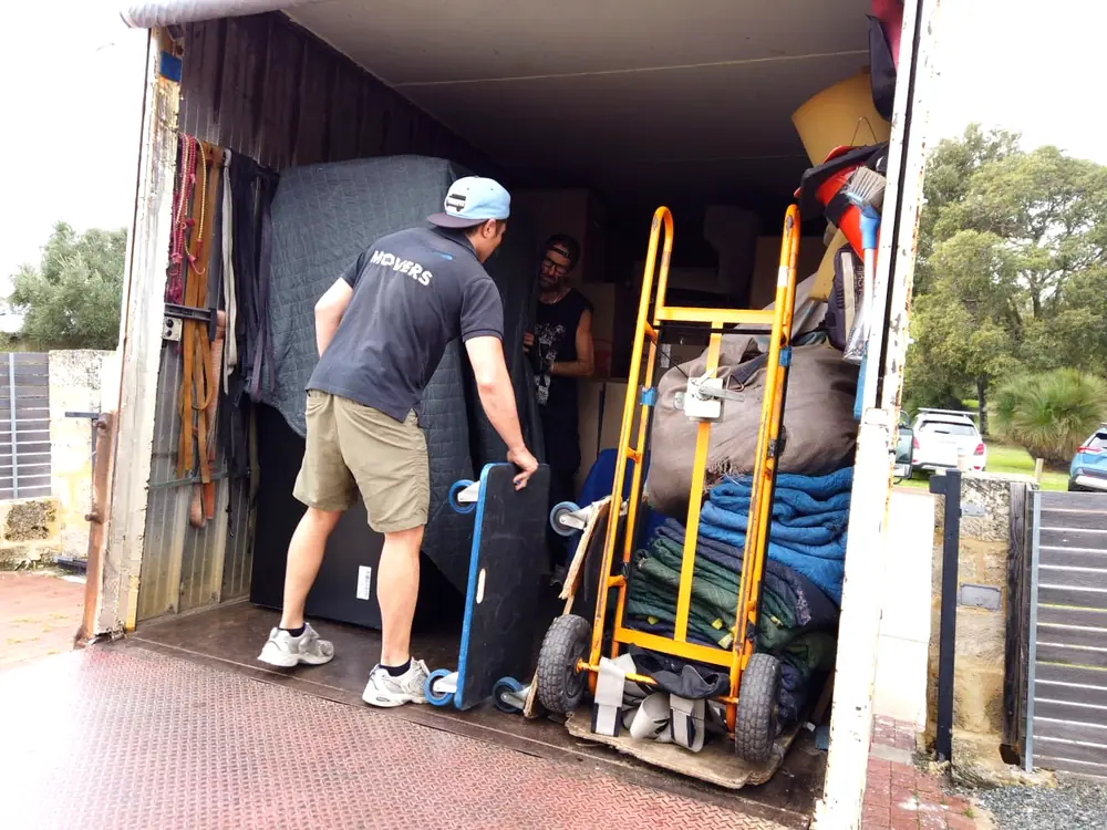 Furniture Removalists Perth movers loading a wrapped mattress beside a trolley of moving blankets